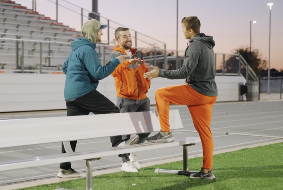 Three coaches talking on the sidelines.