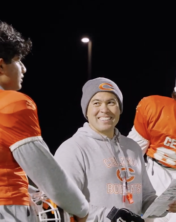 Coach smiling at player under stadium lights