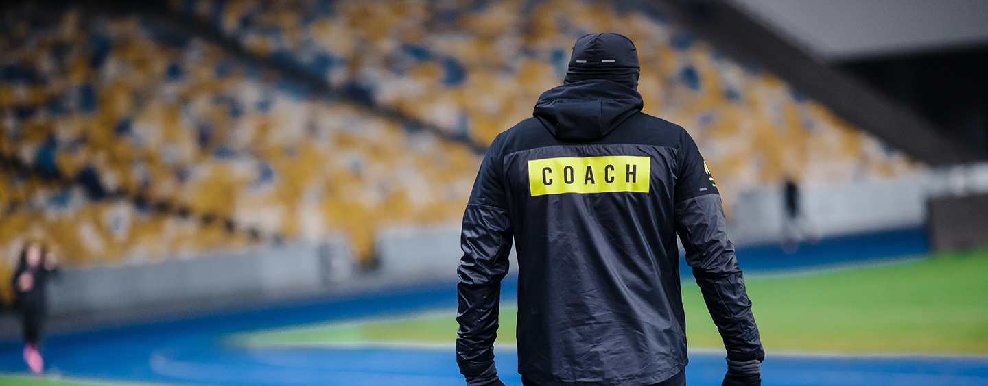 Coach looking down the feild of a crowded football stadium.
